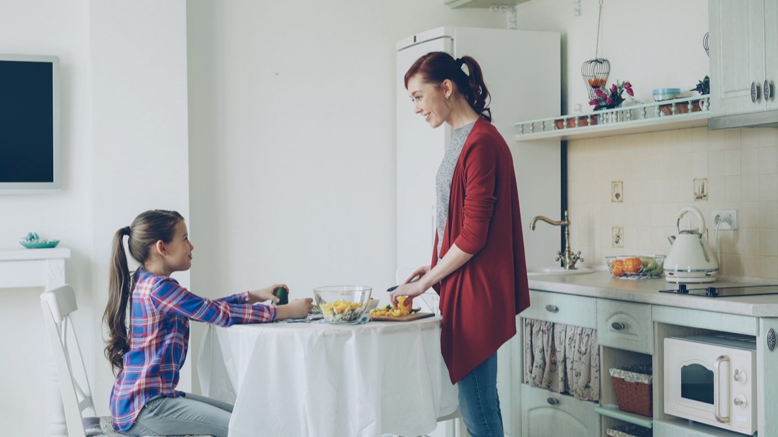A mother and daughter talking in the kitchen before school