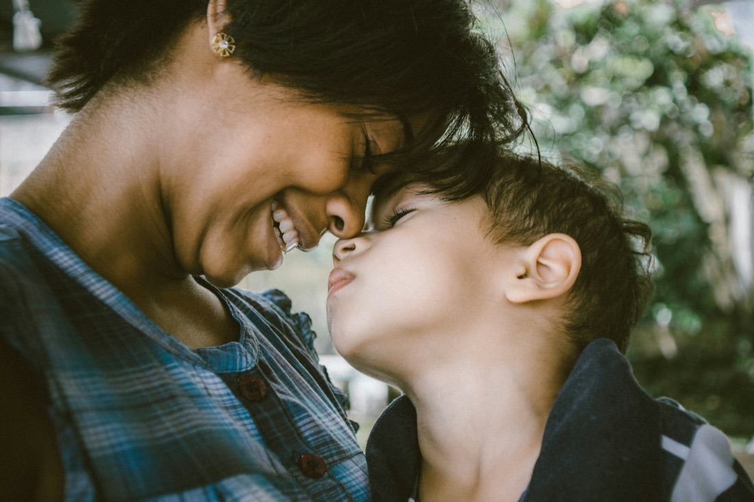 A mother and her son touching foreheads, both smiling