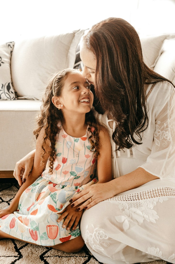 A mother kissing her smiling daughter on the forehead