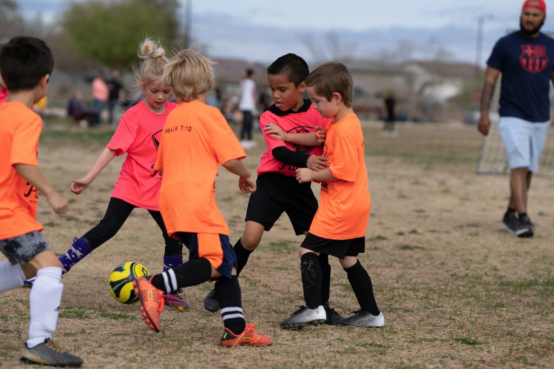 Young kids chasing a soccer ball at practice